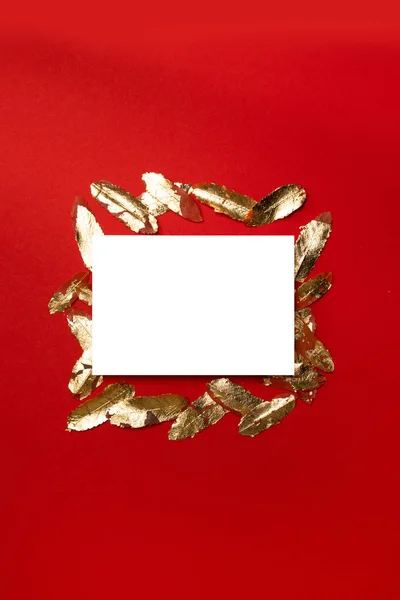 Composición vertical creativa con plantilla de postal blanca en blanco con hojas de oro sobre fondo rojo . — Foto de Stock