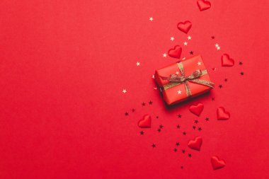 Güzel bir hediye, parlak bir kurdele ve kırmızı arka planda sevgi dolu bir kalp ile Sevgililer Günü festivali arka planı..