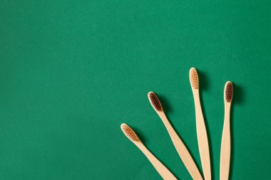 Yeşil arka planda eko bambu ağacı diş fırçaları olan düz konsept veya üst görünüm. Sıfır atık ve çevre bakımı kavramı