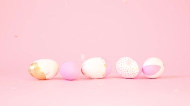 Pembe arka planda altın desenli, paskalya beyazı pembe ahşap yumurtalarla en az yaratıcı kompozisyon. Çok renkli bir altın ve pembe bir şeker uçup gidiyor. Paskalya konsepti.