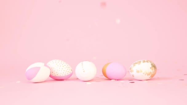 Рожеве золоте конфетті падає на прикрашене яйце візерунка на рожевому фоні. Мінімальна концепція свята. Щасливі великодні листівки — стокове відео
