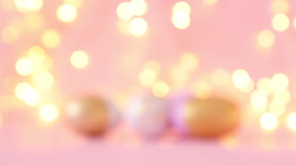 Gold and pink eggs pattern on a light blurry garland. Shallow depth of field. — Stock Video