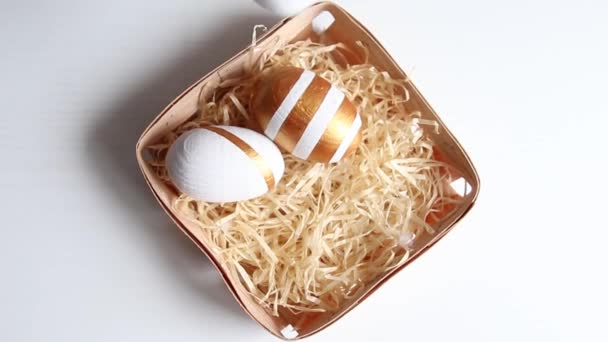 Female hand lays golden decorated easter eggs in a wooden basket. Happy easter — Stock Video