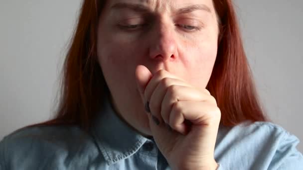Una joven pelirroja con una camisa azul tose pesadamente . — Vídeo de stock