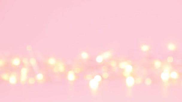 Abstract wazig goud bokeh lichten op een roze achtergrond. — Stockvideo