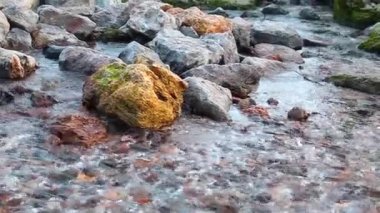 Güneşli bir günde hızlı su farklı boyutlarda taşlarla akar..