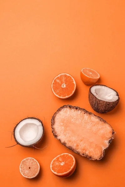 Surtido de frutas exóticas sobre un fondo naranja. Piña, coco, naranja y limón mitad en estilo plano laico — Foto de Stock
