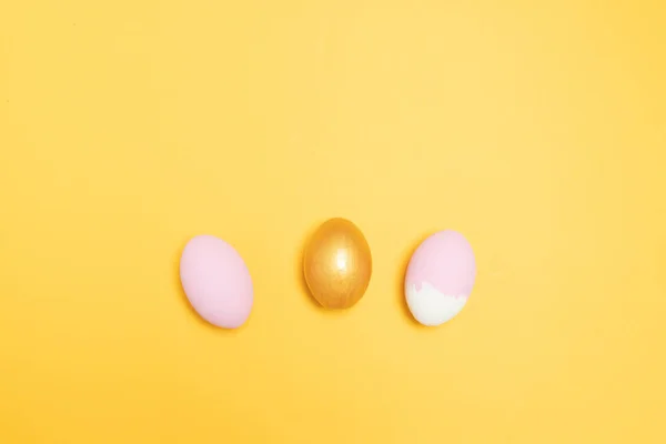 Goud en roze ei op een gele achtergrond — Stockfoto