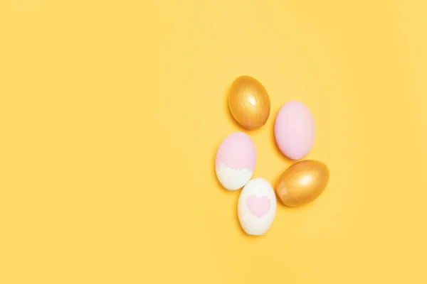 Vista superior de huevos de Pascua dorados y rosados sobre fondo amarillo — Foto de Stock