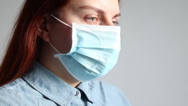 Young red-haired girl in a blue denim shirt in a medical mask. Cold, virus concept — Stock Video