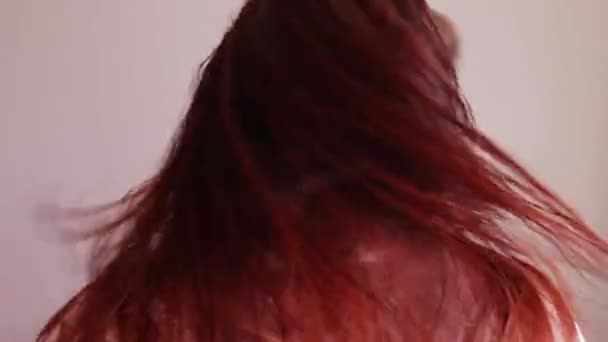 Portrait of a rear view of a young red-haired girl. A woman with wet hair turns her head to the side. Head shake. — Stock Video