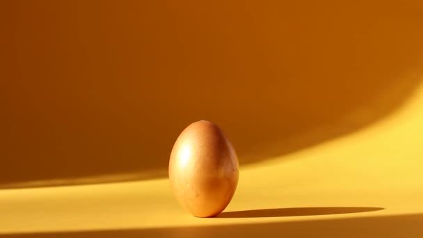 Huevo de Pascua dorado al sol sobre fondo amarillo — Vídeos de Stock