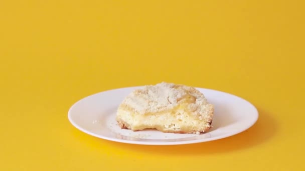 A piece of cake with cottage cheese on white ceramic plate on a yellow background. Female hand takes a piece of cake with a spoon — Stock Video