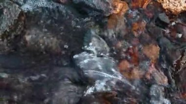 Hızlı nehir kayalıklarda akar. Büyük, gri ve kırmızı taşlar, üst manzara.