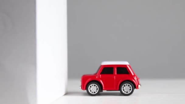 A small red model car crashes into a building wall. Crash test automotive vehicle wall. — Wideo stockowe
