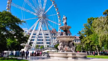 Budapeşte Gözü ve sonbaharda güneşli bir günde tanrı figürleriyle dolu bir çeşme. Açık mavi gökyüzü, cadde boyunca yürüyen bir kalabalık.