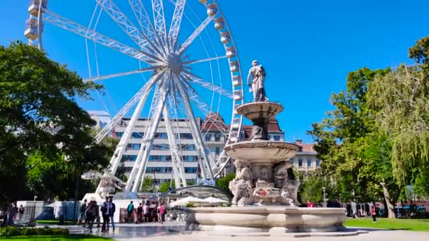 Budapest Eye e una fontana con figure di Dio in una giornata di sole in autunno. cielo blu brillante, una folla di persone che camminano lungo la strada — Video Stock