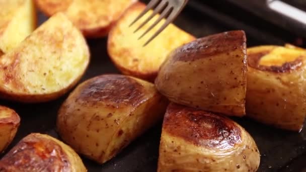 Baked potato slices with spices and salt on a metal pan. Piece of delicious baked potato with rosemary on fork, — Stok video