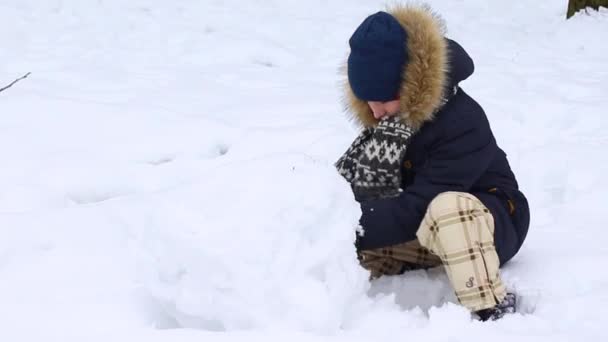 Baby boy sculpts from snow snow snowman — Αρχείο Βίντεο