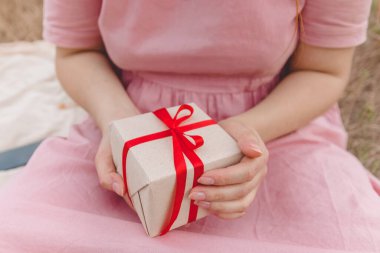 Kadınların elleri sürpriz hediyeler sunuyor. Kırmızı fiyonklu.