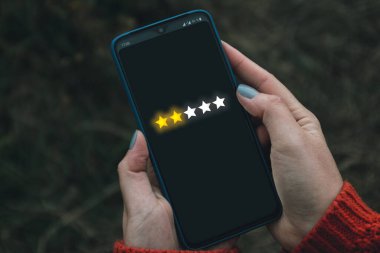 Geri bildirim, gözden geçirme ve değerlendirme kavramını artırma. Ekranda müşteri deneyimi kavramına sahip akıllı telefonu tutmak.