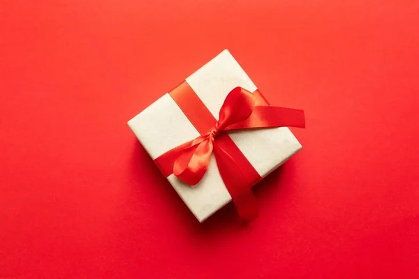 Fondo de fiesta de celebración con caja de regalo y lazo rojo sobre fondo rojo — Foto de Stock