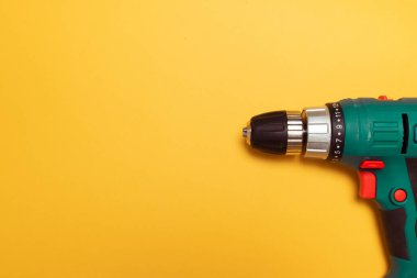 Sarı arka planda yeşil elektrikli matkap, telif alanı, üst manzara, düz. Yapı Araçları