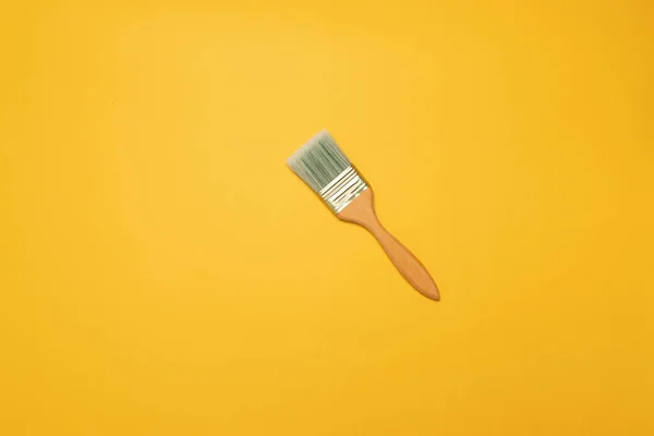 Wooden painters brush on a yellow background — Stock Photo, Image