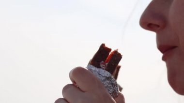 Genç bir kız sabahleyin denizde oturarak sandviç yer. Kadın yüzü yakın çekim..