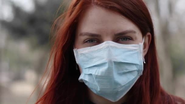 Porträtt av en ung röd hår turist kvinna i en medicinsk mask illamående tittar på kameran. Nytt coronavirus 2019-ncov — Stockvideo