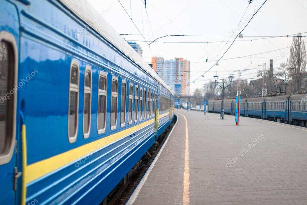 Close of the blue metal railway carriage with clean windows stand on the platform of the train station. Departure or arrival of a train. Travel concept