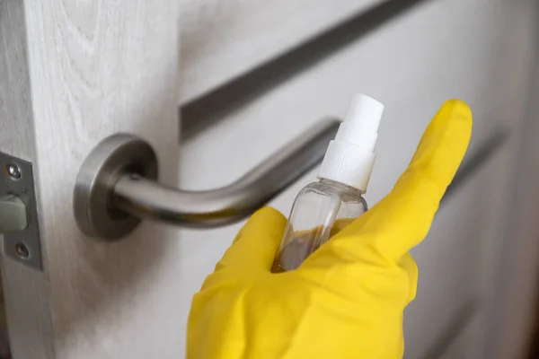 Жінка дезінфікує і очищає дверну ручку антибактеріальним дезінфікуючим засобом для захисту від вірусів, мікробів — стокове фото