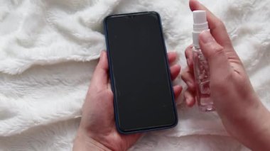 El, mikroplardan, virüslerden ve bakterilerden cep telefonuna alkol ve dezenfektan püskürtüyor.