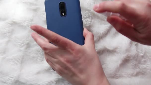 Κοντινό πλάνο των γυναικείων χεριών ψεκασμού απολυμαντικό σε ένα κινητό τηλέφωνο για τον καθαρισμό και την προστασία από ιούς, βακτήρια και μικρόβια — Αρχείο Βίντεο