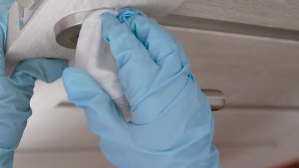 Guanti di gomma di lattice umani in blu spruzza e pulisce una maniglia da germi, virus e bacrea in una casa, in ufficio o in ospedale . — Video Stock