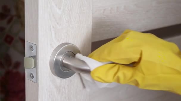 Un hombre con guantes de goma de látex amarillo limpia un pomo de la puerta de gérmenes, virus y bacterias en una casa, oficina u hospital — Vídeo de stock