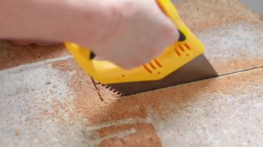 İşçi yakın mesafeden el testeresi kullanır ve evde ahşap bir kalkan keser. Çizgili tahta malzemesinden bir sürü talaş. İnşaat konsepti