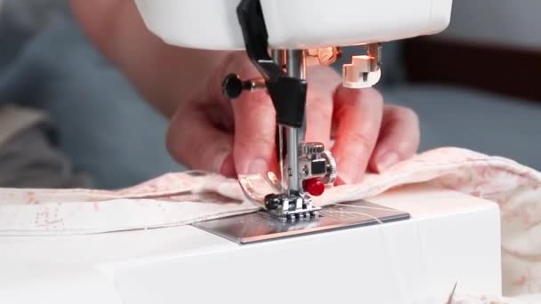 Le mani femminili cuciono la maschera medica da tessuto di cottone su una macchina per cucire. Vista ravvicinata del processo di cucito . — Video Stock