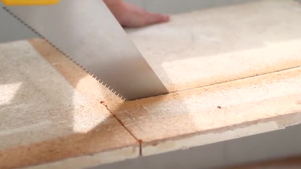 Primo piano di mano umana ha bevuto una tavola di legno con una sega a mano alla luce del sole a casa — Video Stock