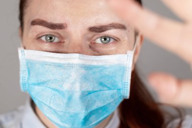 Tıbbi maskeli bir doktor ve dur işaretli bir el. Tıbbi personele yardım.