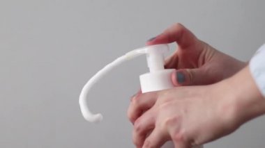 Kadın beyaz plastik pompa şişesine el basıp daha temiz köpük alıyor. Sıvı köpük sabunlu dağıtıcı
