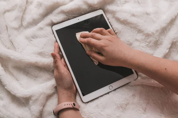 Cleaning a dirty tablet gadget screen with a spray against germs, dust and viruses. Health and Medicine