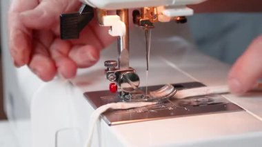 Dikiş işleminin görüntüsünü kapat. Koronavirüs salgını sırasında dikiş makinesine pamuk kumaştan tıbbi maske dikmiş.