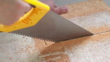 İnsan eli testere kullanır ve evde ahşap bir kalkan keser. Çizgili tahta malzemesinden bir sürü talaş. İnşaat konsepti