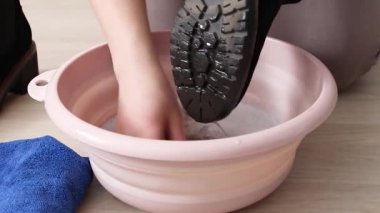 Ayakkabı temizleme. Kapalı kadın ayakkabılarını pembe plastik leğenle yıkıyor.