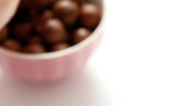İnsan eli pembe bir kaseden macadamia fındığı alır ve ceviz kırmızısını ortaya çıkarır.