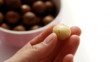 Kadın eli bulanık arka planda Macadamia fıstığını tutuyor.