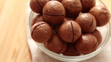 Cam kasede bir sürü taze Macadamia fındığı, ahşap bir yüzeyin üst manzarası. Düz yatıyordu. Yiyecek konsepti.