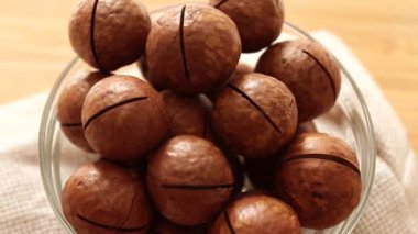 Cam kasede taze Macadamia fındıkları, ahşap bir yüzeyin üst manzarası. Düz yatıyordu. Yiyecek konsepti.
