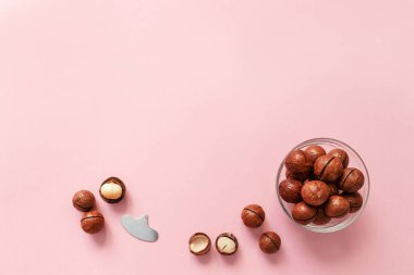Organik Macadamia fındıkları ve pembe arkaplandaki yazı için boşluk, üst görünüm